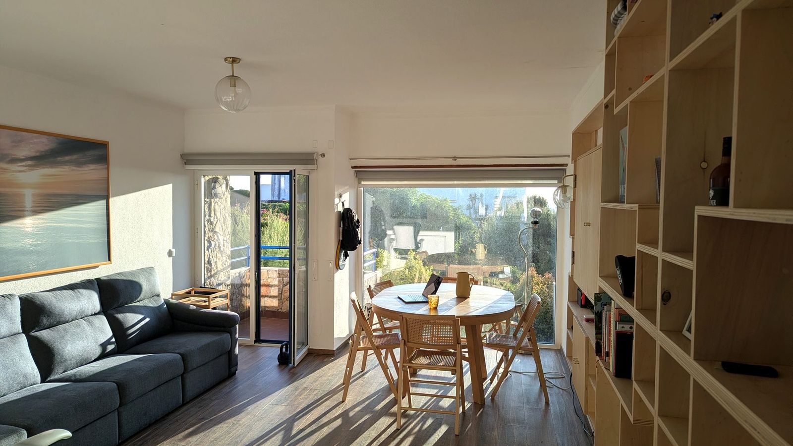 Living room with the dining table and the balcony door, in evening light.