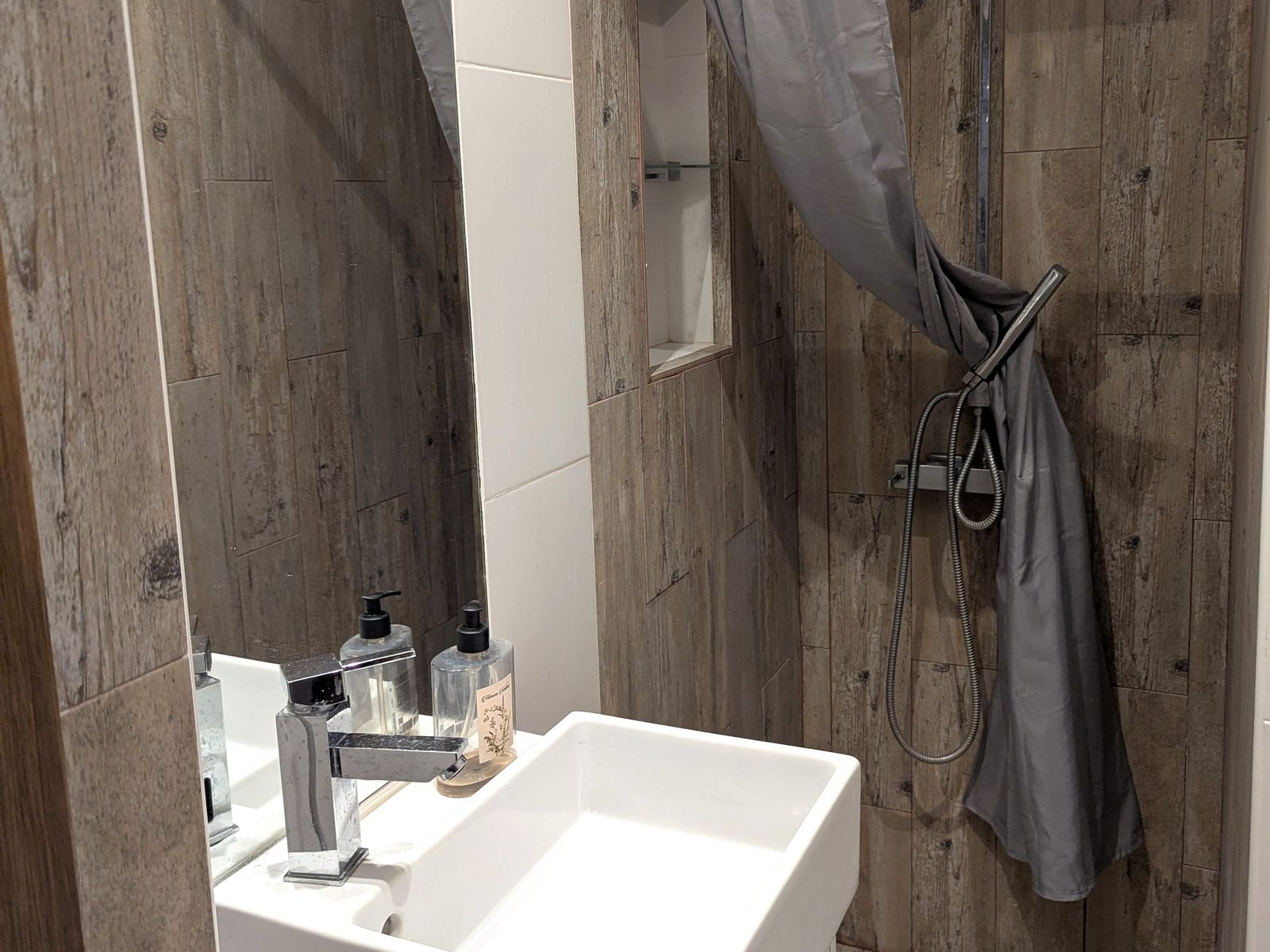 Bathroom with a basin, mirror and walk-in shower.